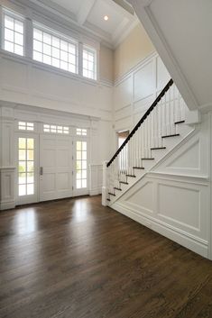 an empty living room with wood floors and white railings on the second story stairs