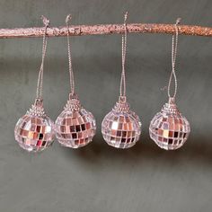 three disco ball ornaments hanging from a tree branch