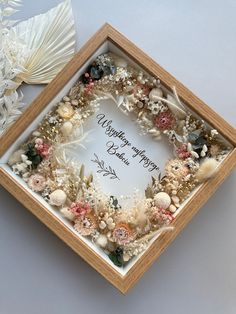 a wooden frame holding a card with flowers and seashells