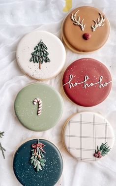 four decorated cookies sitting on top of a white tablecloth covered in frosted icing