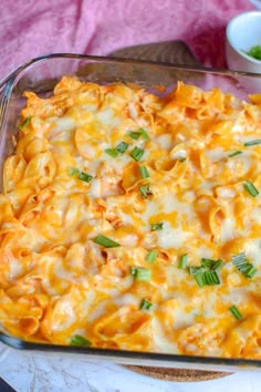 a casserole dish with cheese and green onions in it sitting on a table