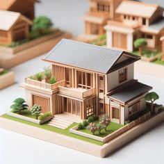 a model of a house with trees and bushes on the ground next to other small houses