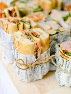 several sandwiches wrapped in paper on a table