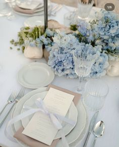 the table is set with blue and white flowers, silverware, and napkins