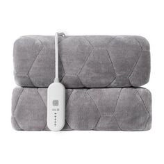 two gray bedspreads sitting next to each other with an electronic device on top