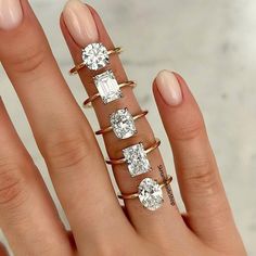 a woman's hand with five different rings on it and one diamond ring in the middle