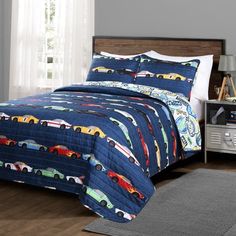 a bed with a blue bedspread and cars on it in a bedroom next to a window