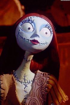 an animated doll with red hair and blue eyes wearing a white dress is looking at the camera