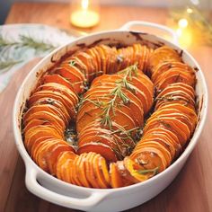 a casserole dish filled with sweet potatoes and topped with fresh thyler sprigs