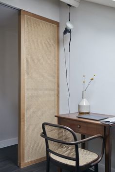 a room with a desk, chair and lamp on it in front of a door