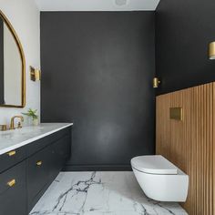 a white toilet sitting next to a bathroom sink under a mirror on top of a wooden cabinet