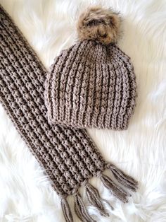 a knitted hat and scarf laying on top of white fur