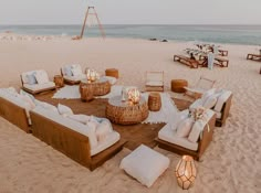 an outdoor seating area is set up on the beach with candles and flowers in vases