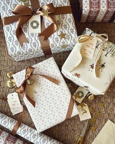 presents wrapped in brown and white paper with bows on them sitting on the floor next to each other