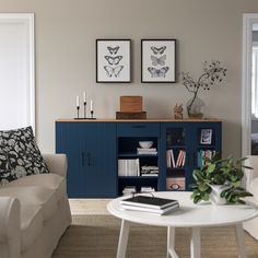 a living room filled with furniture next to a white table and two framed pictures on the wall