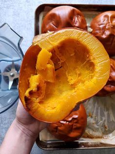 a person holding up a half eaten pumpkin in front of some other food on a tray