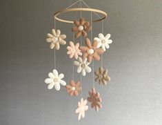 a mobile made out of felt flowers hanging from a string on a gray wall background