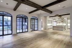 an empty living room with wood floors and large windows