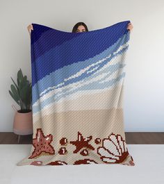 a woman is holding up a blanket that has shells on it