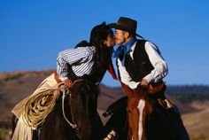 a man and woman riding on the backs of horses