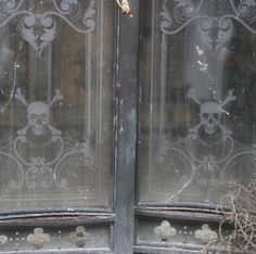 an old door with skulls and bones painted on the glass, in front of a building