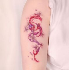 a woman's arm with a dragon and flowers tattoo on the left side of her arm