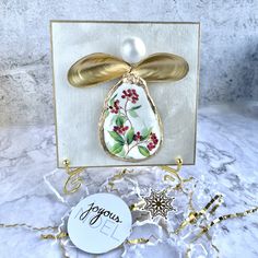 a white card with gold accents and a flower design on it, next to a tag that says joy