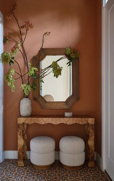 a mirror sitting on top of a wooden table next to a vase filled with flowers