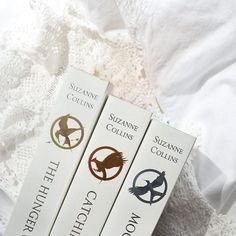 three books sitting on top of a bed next to each other in front of a white sheet