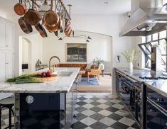 a kitchen with black and white checkered flooring, pots hanging from the ceiling