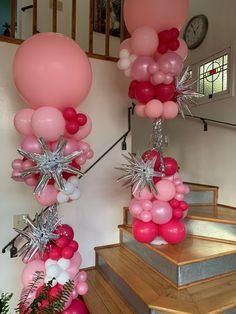 some pink and white balloons are on the stairs