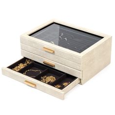 two drawers with gold jewelry in them on a white surface, one open and the other closed