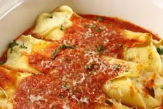 a white bowl filled with pasta covered in marinara sauce and parmesan cheese