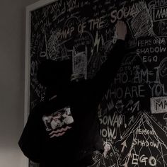 a man standing in front of a blackboard with writing on it