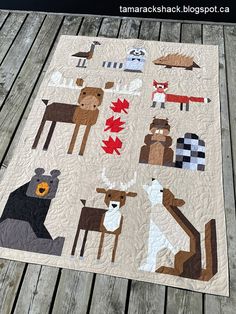 a quilt with animals on it sitting on a wooden deck