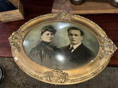 an antique portrait of two people in formal dress sitting on a table next to other items