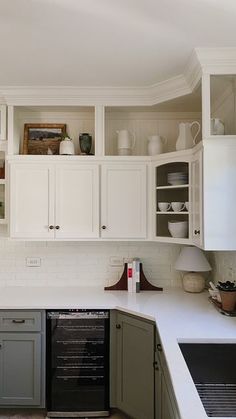 a kitchen with white cabinets and gray appliances