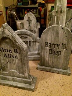 three cement tombstones with carved heads and names on them sitting on a counter top