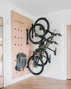 there is a bike hanging on the wall with two bikes mounted to it's back