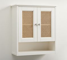 a white wall mounted cabinet with wicker doors