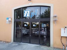 the front entrance to a store with glass doors and parking meters on the side walk