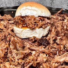 a pulled pork sandwich sitting on top of a black tray