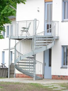 a metal spiral staircase next to a white building