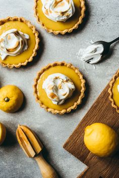 lemon meringue tarts with whipped cream on top and wooden utensils