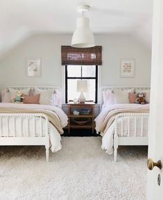 two beds in a bedroom with white rugs and pillows on top of the bed