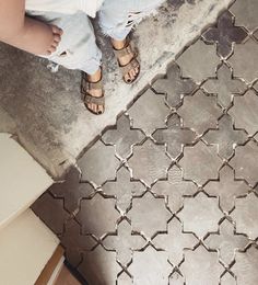 a person standing on a tile floor with their feet up and one foot in the air