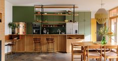 an open kitchen and dining room area with wooden flooring, green cabinets and shelves