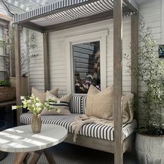 a couch sitting on top of a patio next to a white table and potted plants