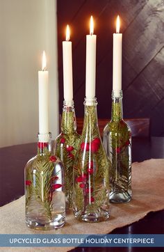 three bottles with candles in them sitting on a table next to each other and the words upcycled glass bottle holiday centerpiece