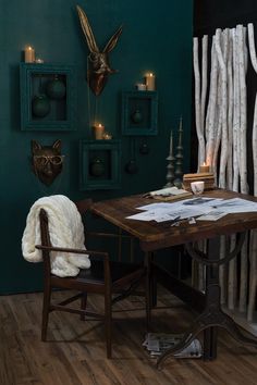 a room with green walls and wooden flooring is furnished with an antique desk and chair